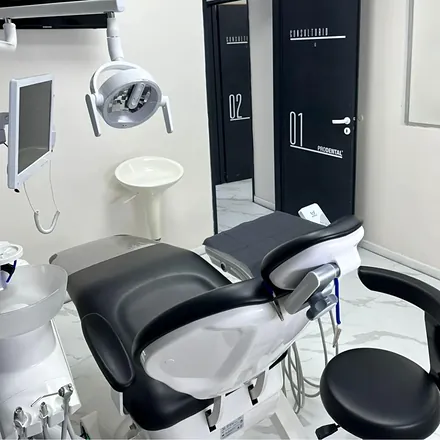 Box de atención con el sillón negro, la lámpara y las puertas de los consultorios 01 y 02