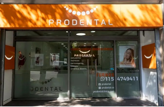 Fachada a la calle con el toldo naranja de Prodental y la vidriera