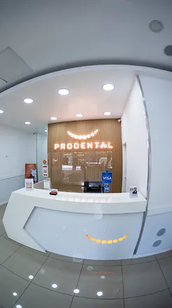 Recepción con el mostrador blanco y el cartel PRODENTAL sobre la pared de listones de madera